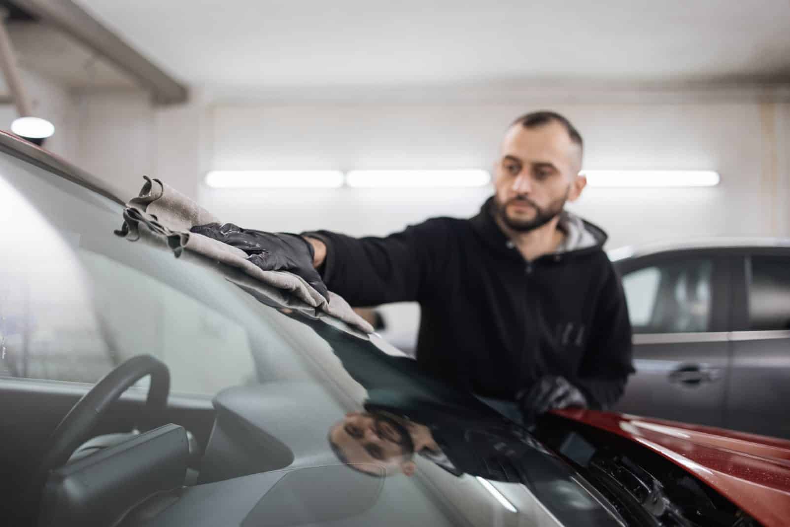 mężczyzna przeciera szybę samochodową